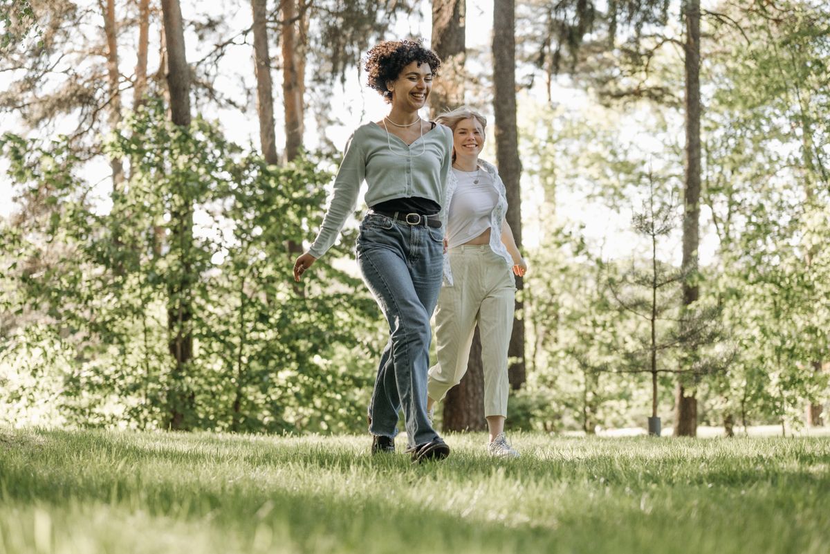 A happy couple running together through a sunlit forest