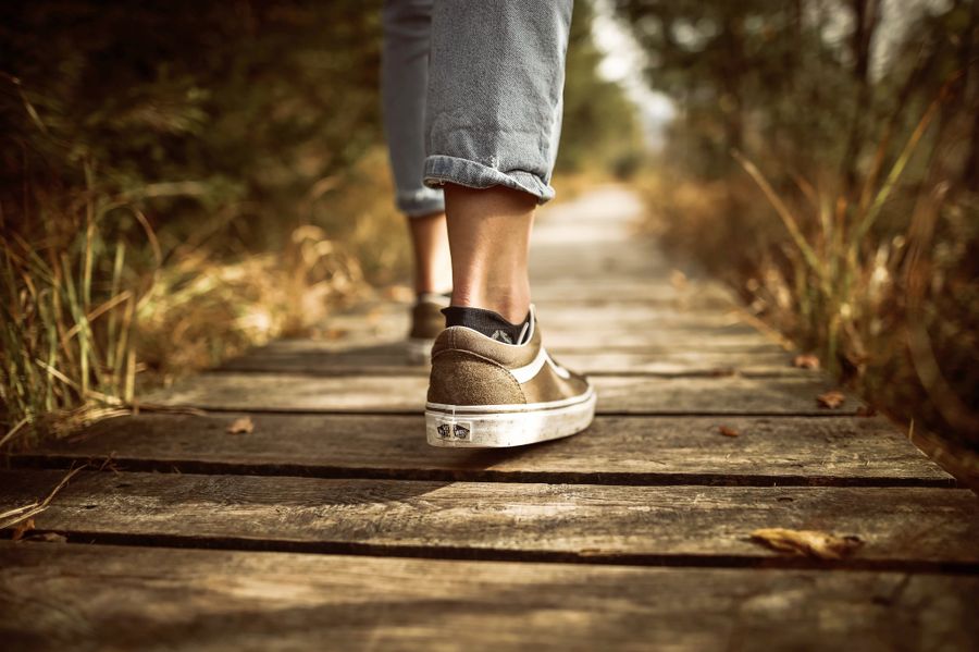 A person walking on a peaceful wooden path through a green park
