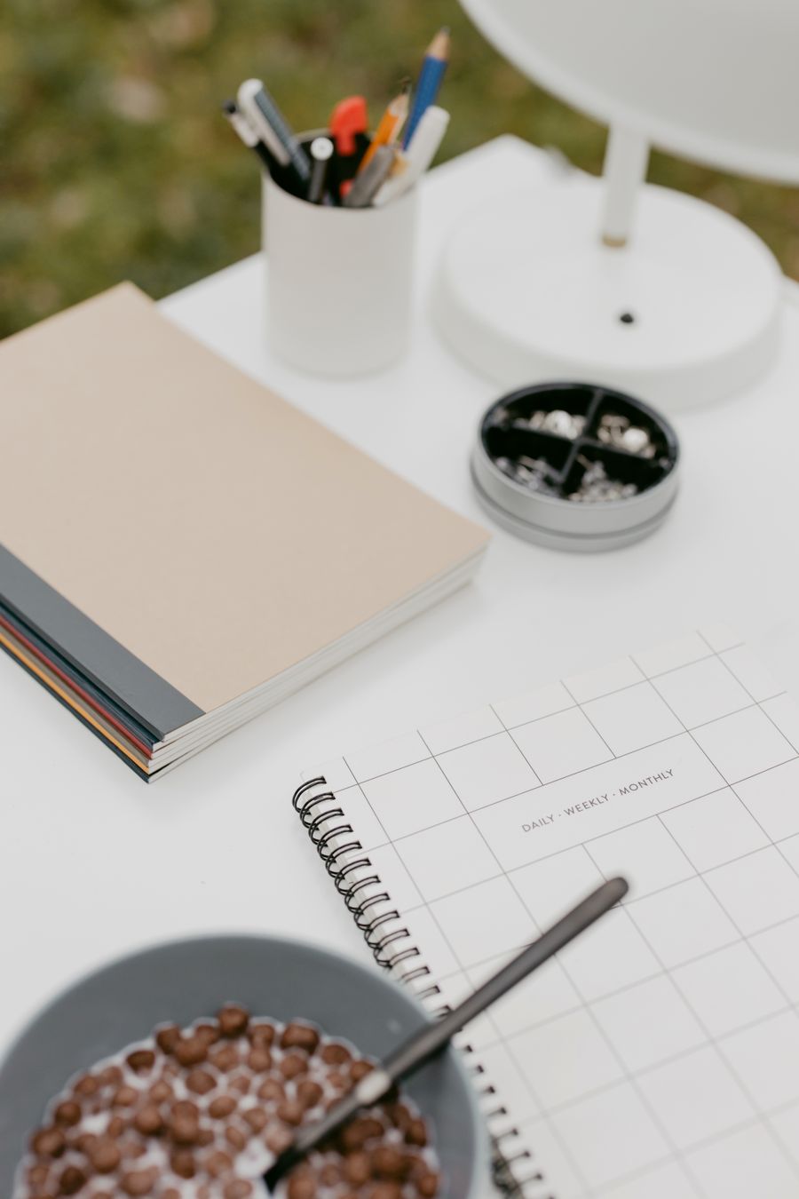 A tidy, plant-lined home workspace with notebooks and breakfast