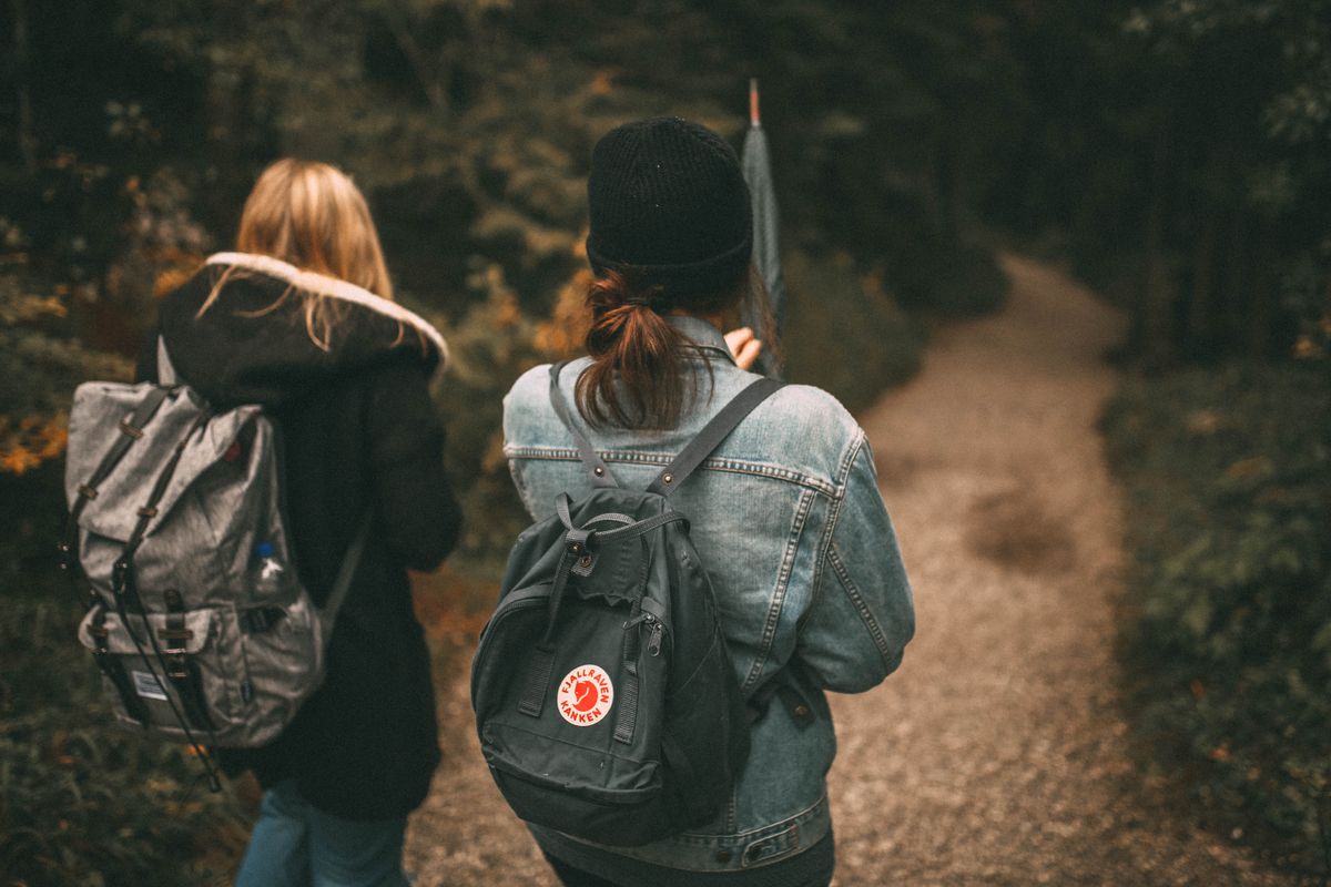Two friends exploring a forest trail together with backpacks