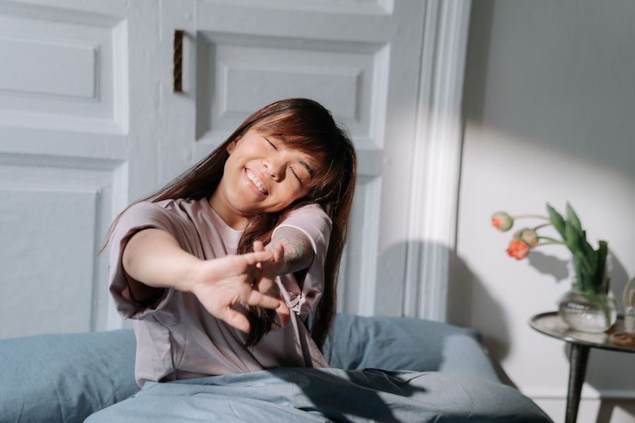 A woman gently stretching in soft morning light after waking